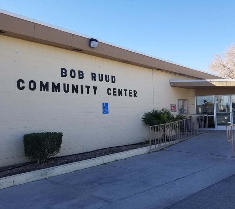 Exterior of Bob Ruud Community Center with ramp, sign, and clear blue sky.
