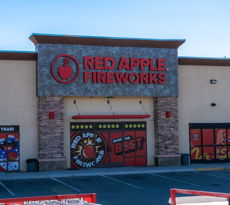 Storefront of Red Apple Fireworks with large red signage and promotional decorations on the windows.