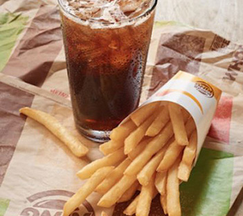 A glass of soda and a serving of French fries on a fast food wrapper.