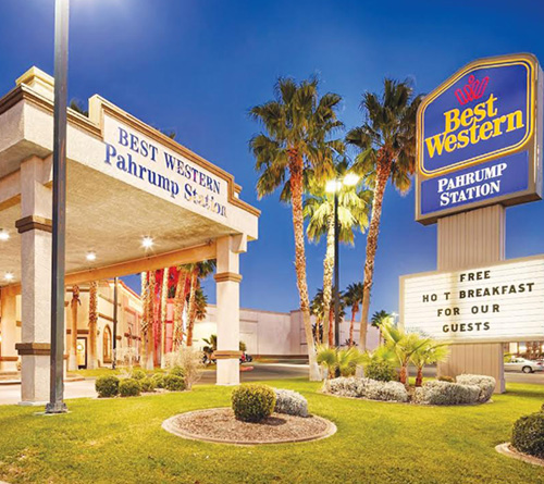 Best Western Pahrump Station hotel entrance with palm trees and sign offering free hot breakfast.