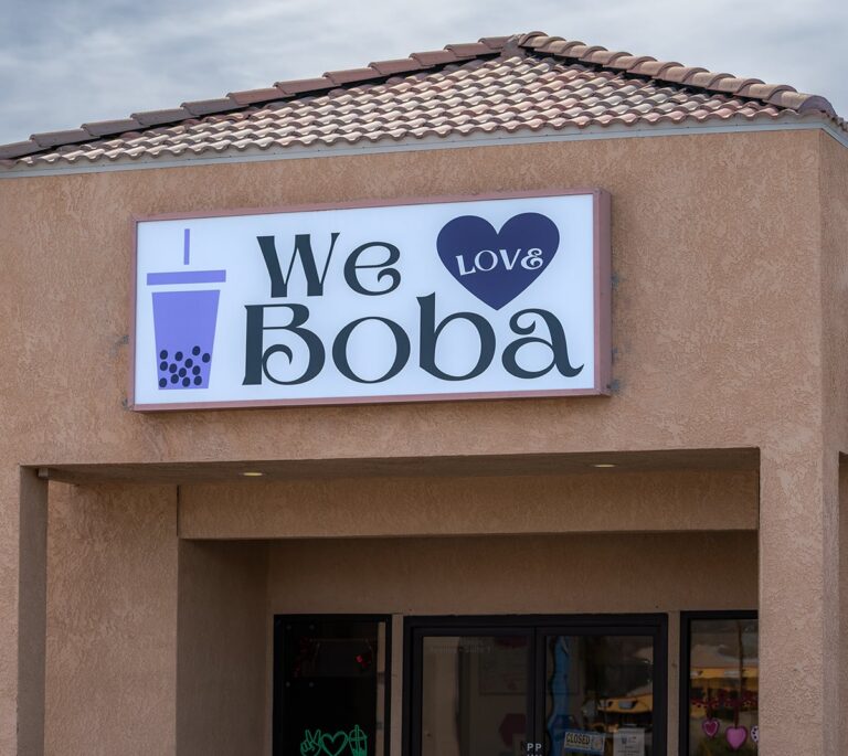 A shop sign reads We Love Boba with a heart and a cup of bubble tea illustrated next to the text.