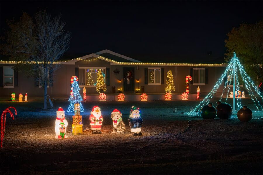 A house decorated with Christmas lights, Santa figures, and glowing trees at night.
