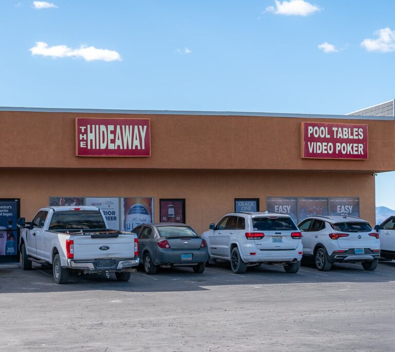 Four cars parked outside a bar called The Hideaway, which advertises pool tables and video poker.