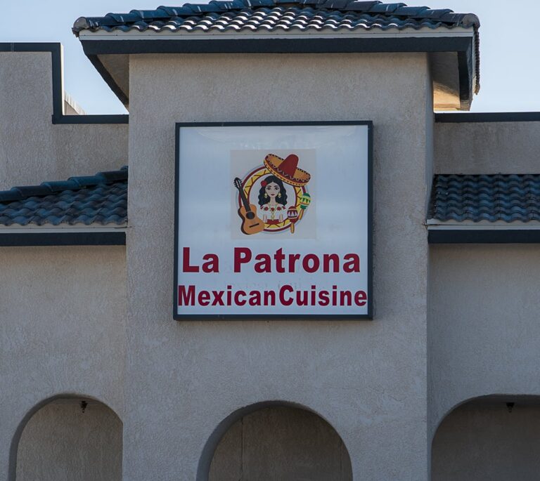 Sign for La Patrona Mexican Cuisine with a cartoon woman in a sombrero and guitar above the text.