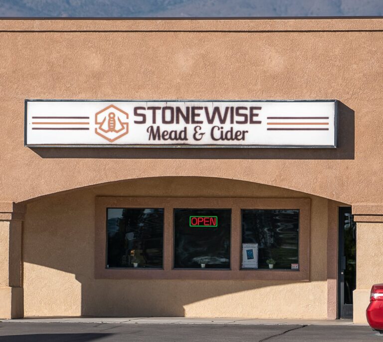 Storefront with a sign reading STONEWISE Mead & Cider above a window with a glowing OPEN sign.