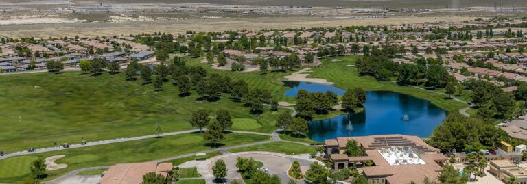 Aerial view of a suburban neighborhood with a golf course, lake, and green spaces surrounded by houses.