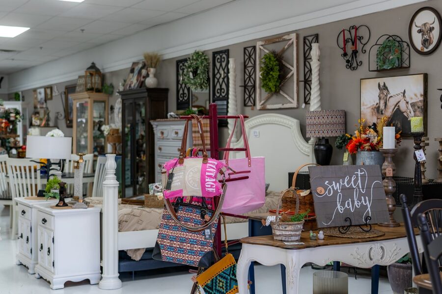 Home decor store with furniture, bags, wall art, lamps, and a sweet baby sign on display.