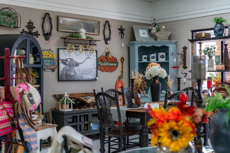 A cozy shop with home decor, wall art, flowers, and wooden furniture on display.
