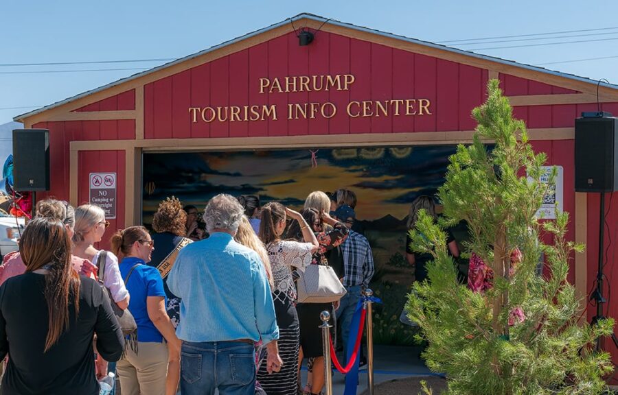 People line up outside the red Pahrump Tourism Info Center on a sunny day.