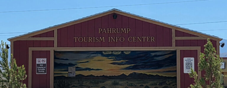 Red building labeled Pahrump Tourism Info Center with a painted desert sunset mural and QR code signs.