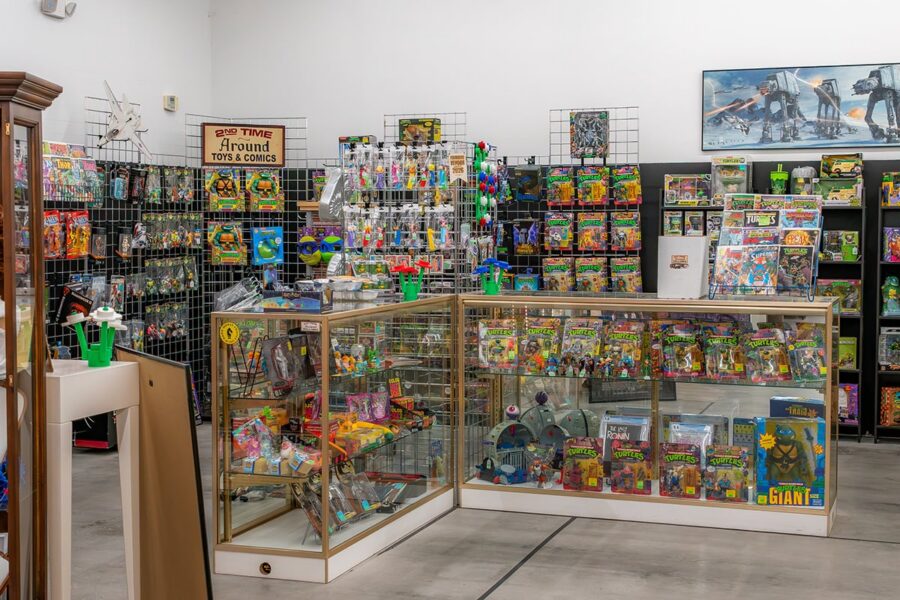 Glass display cases and shelves filled with vintage toys and action figures in a collectibles store.