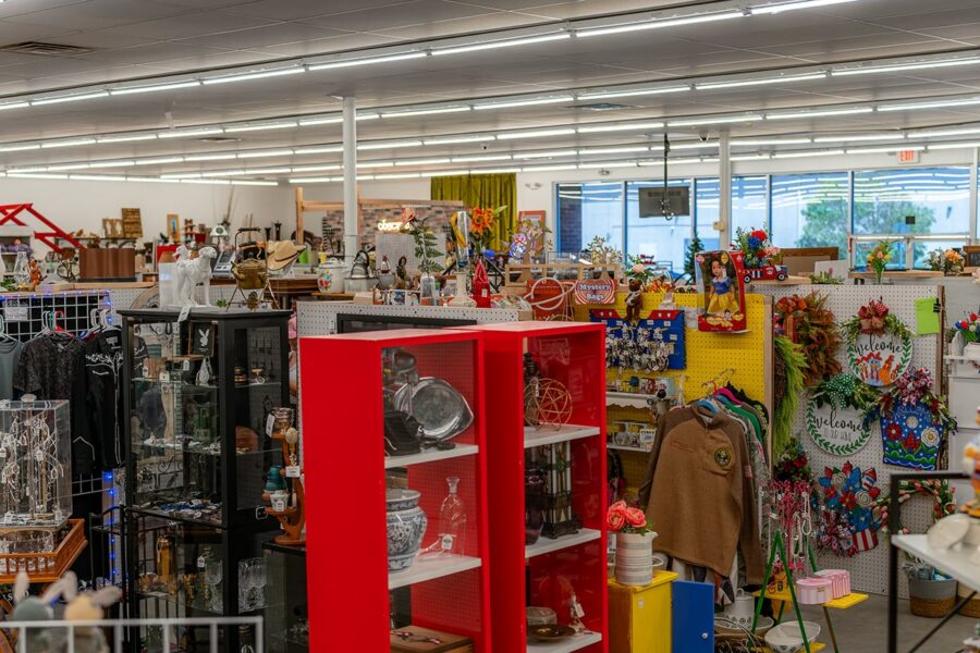 Thrift store interior with shelves full of various home decor, kitchenware, and colorful items.