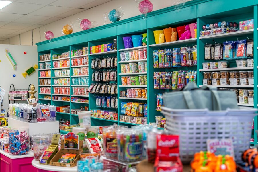 Colorful candy store with shelves of packaged sweets, bins, and displays filled with various treats.