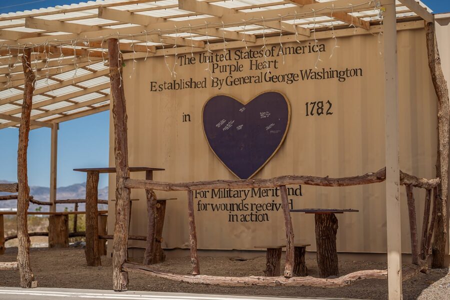 Outdoor memorial with wooden benches and a wall honoring the Purple Heart, established in 1782 by George Washington.