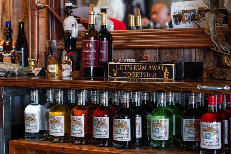 Bottles of liquor on wooden shelves with a sign saying LETS RUM AWAY TOGETHER and a mirror above.