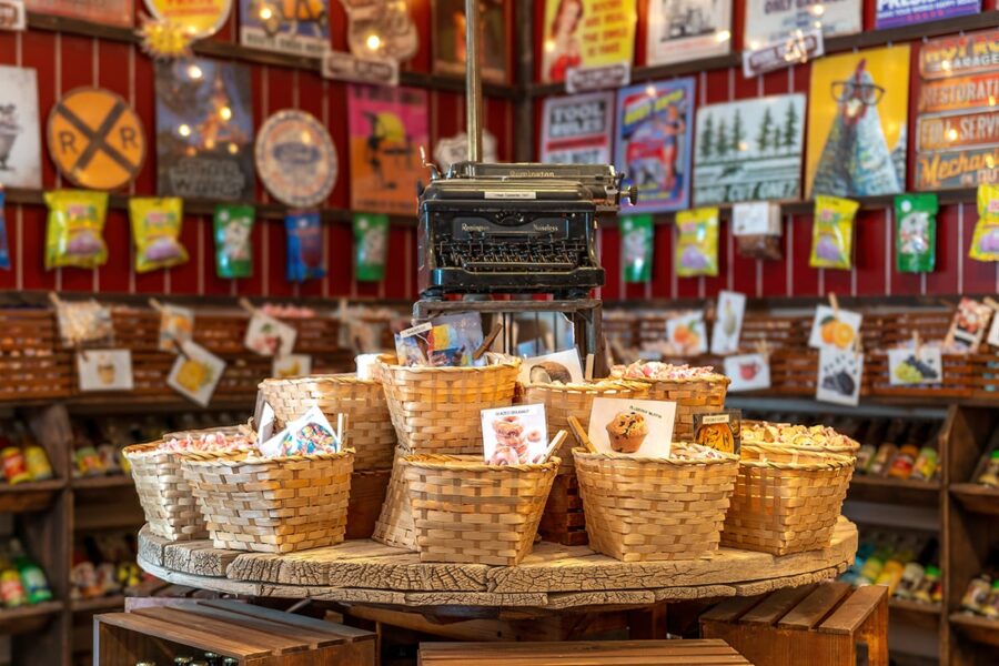 Baskets of candy on a round wooden table with a typewriter on top, in a colorful vintage store.